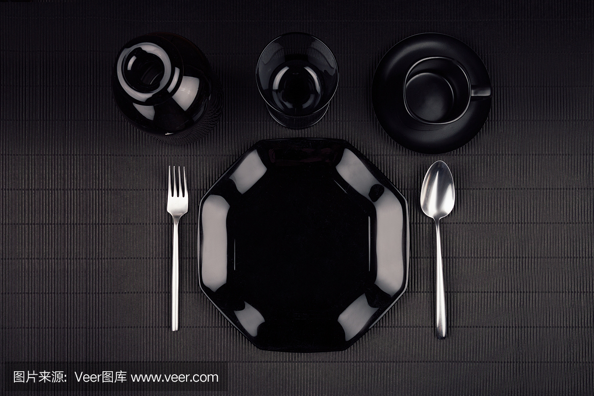 黑色盘子与餐具在黑暗的现代极简主义席子背景,俯视图。